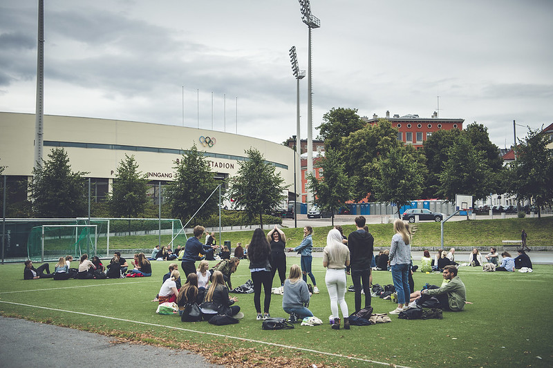 En gruppe studenter som står og sitter i sirkel på en fotballbane. En av studentforeningene som driver med idrett.